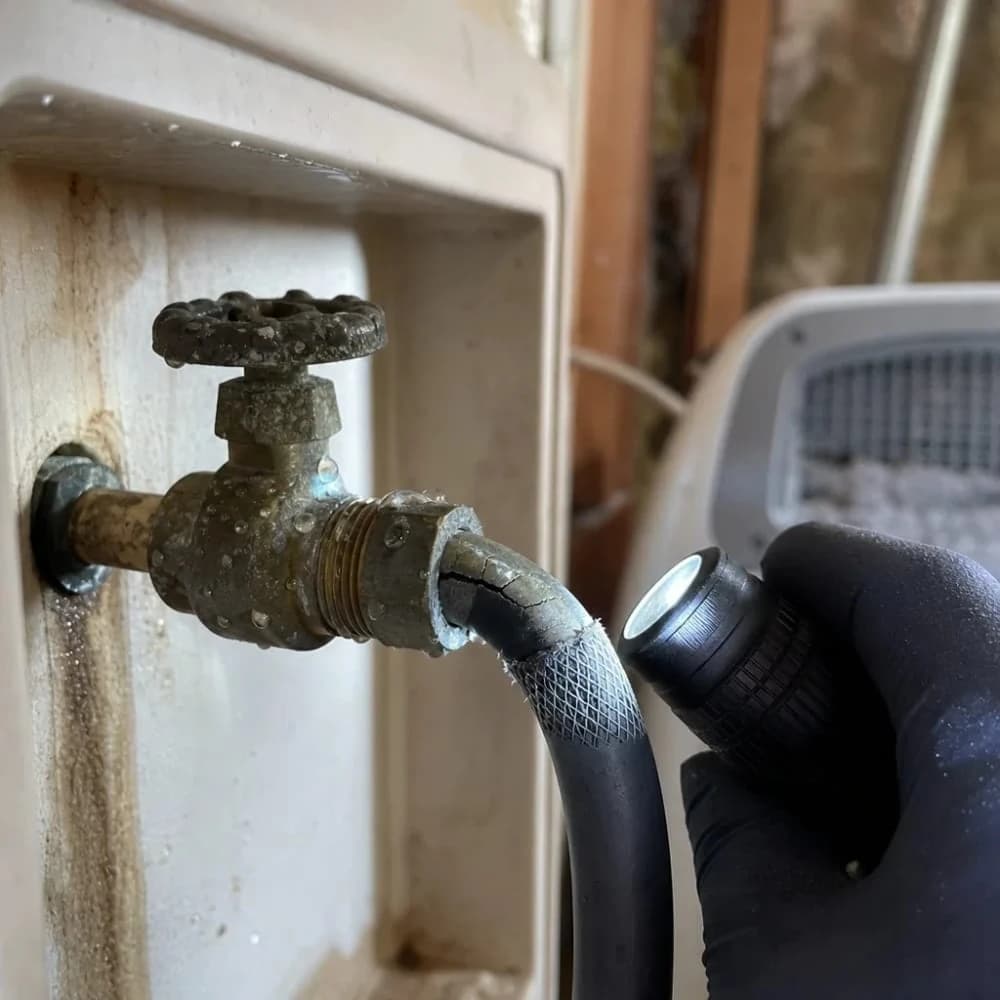 Close-up of corroded washing machine hose valve leaking in wall box