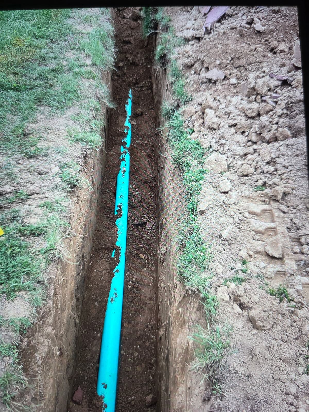 Plumbing repair in Evansville, IN — blue water service pipe laid in a lawn trench
