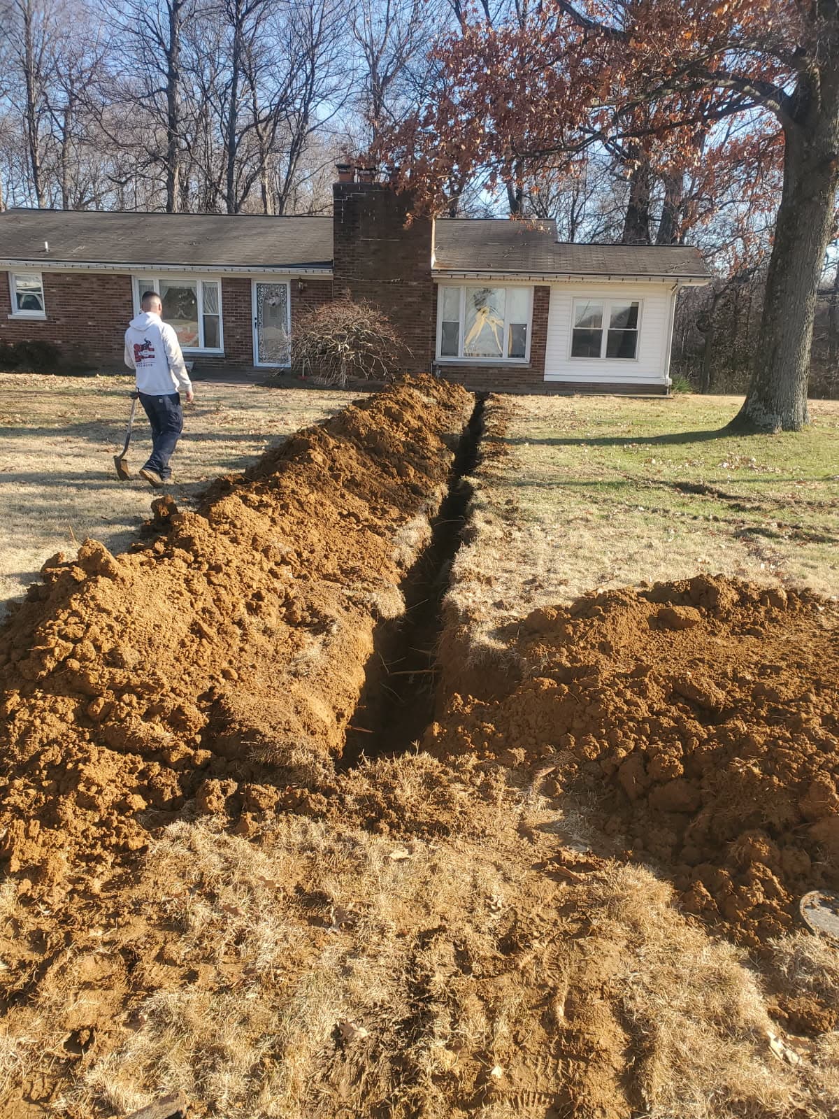 Plumbing repair in Evansville, IN — water line trench through a front yard to a brick ranch