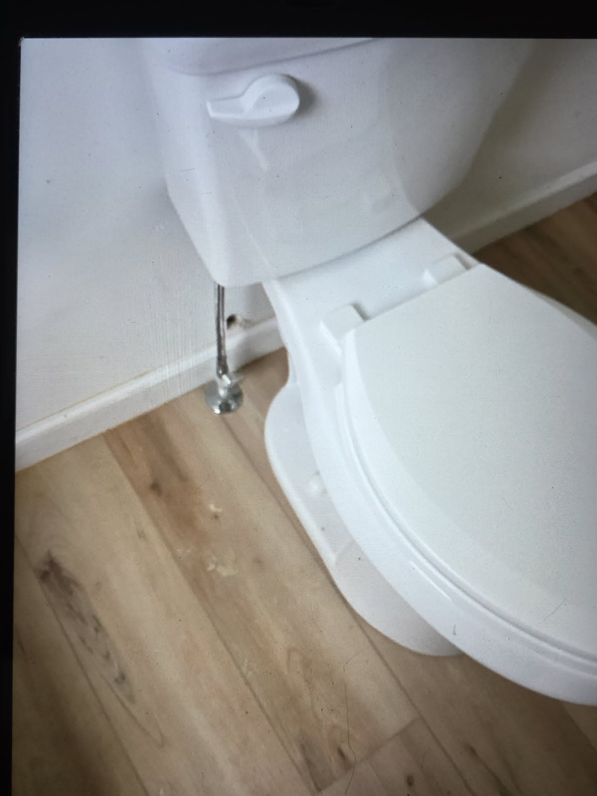 Residential plumber in Evansville, IN — toilet replacement on wood flooring with chrome supply