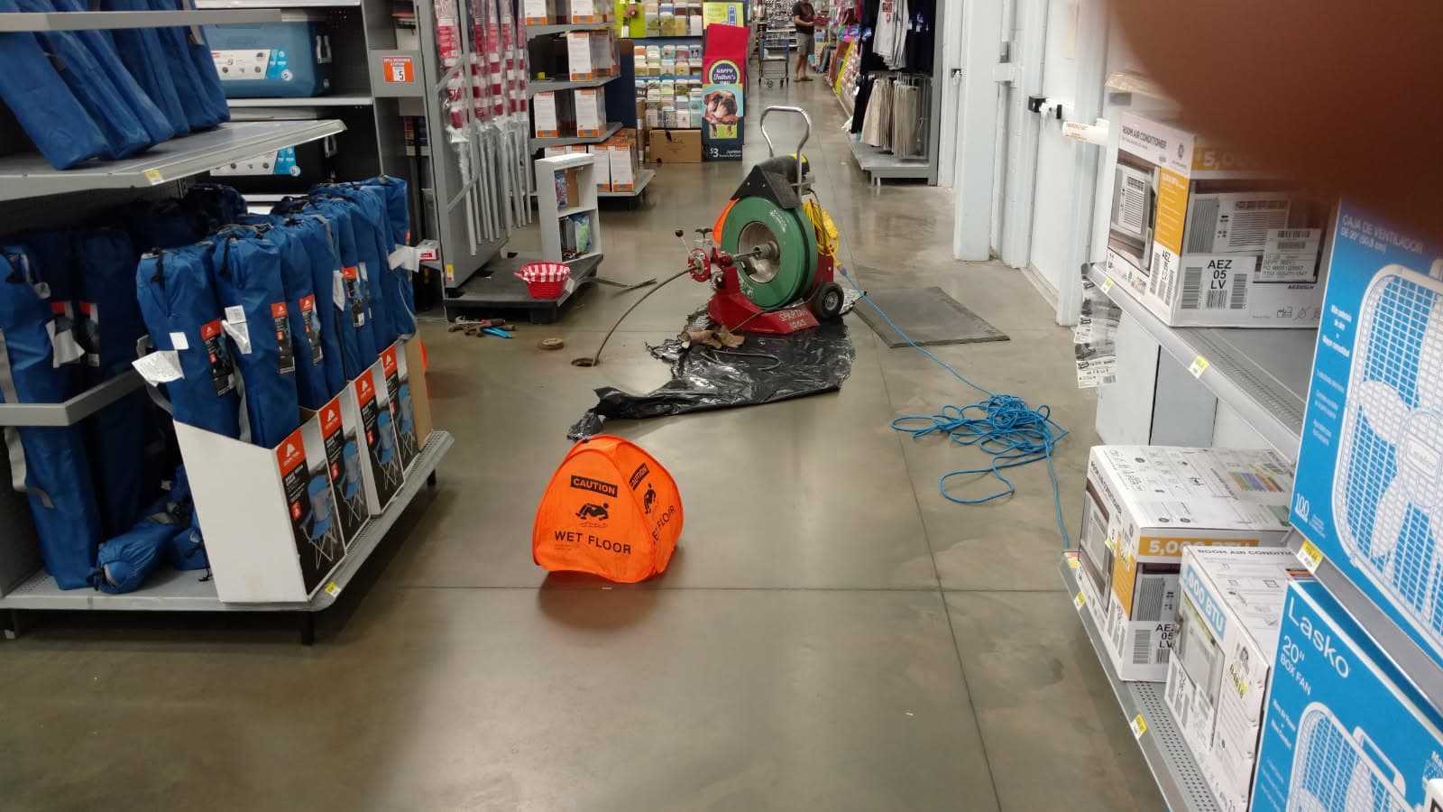 Commercial plumber in Evansville, IN — drain machine clearing a floor cleanout in a retail aisle