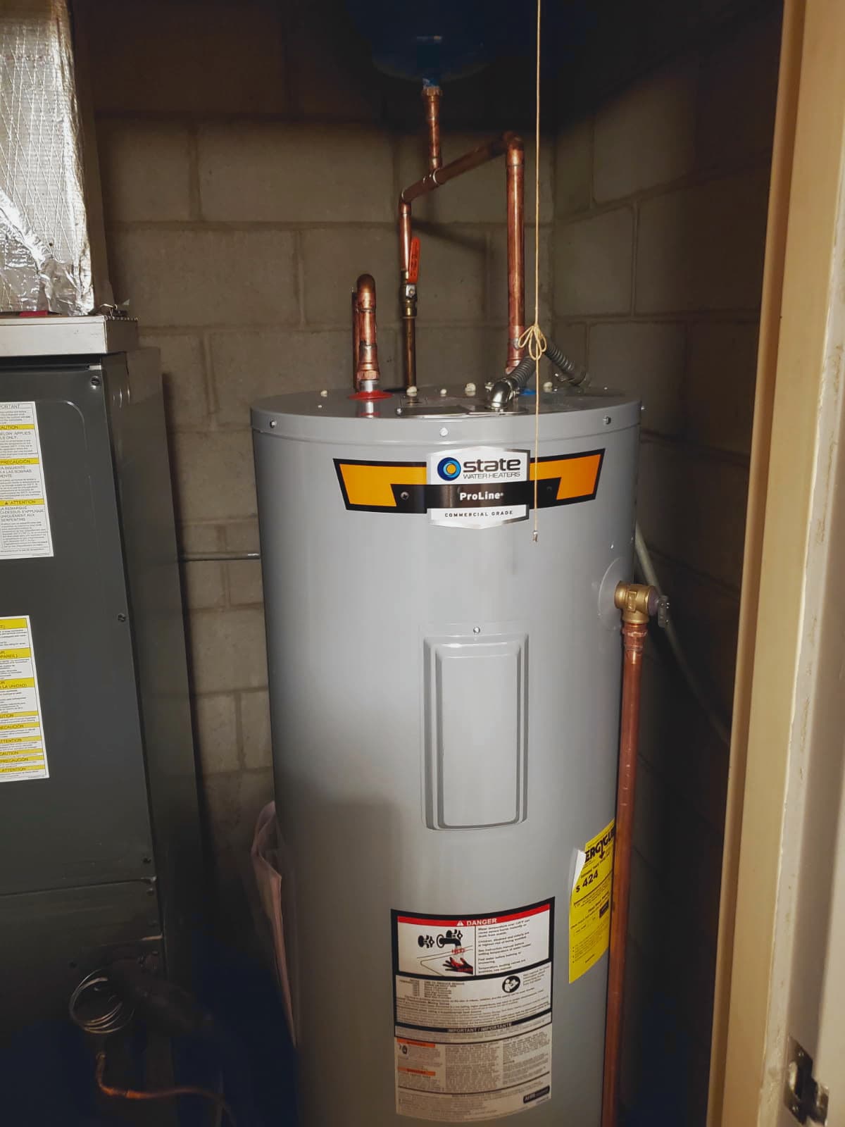 Plumber in Evansville, IN — tank water heater with copper pipes in a utility closet