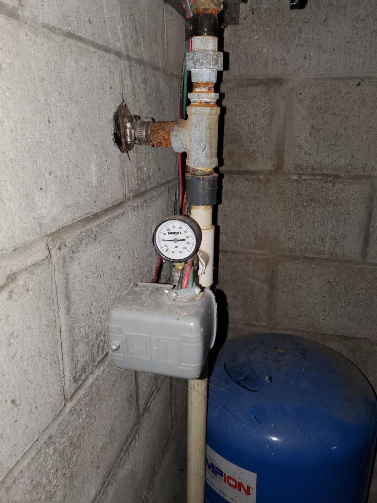 Well pump and pressure tank in Evansville, IN — blue Champion pressure tank with a pressure gauge on a block wall